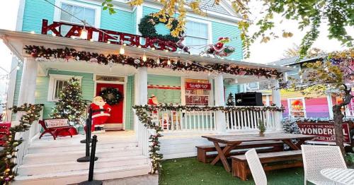 A festive house decorated for Christmas with lights, a Santa figure, and a cheerful sign reading "Katiebug's."