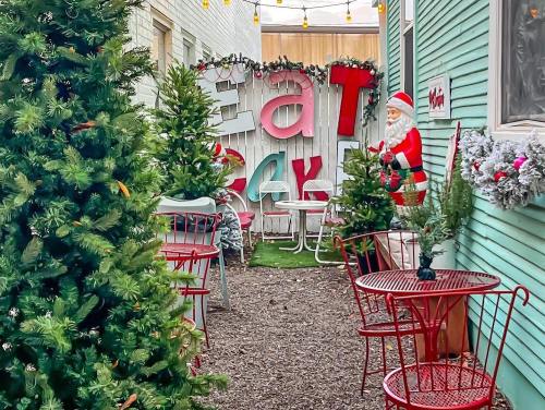 A festive outdoor space with red tables, Christmas trees, and Santa decorations, creating a cheerful holiday atmosphere.