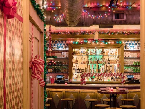A festive bar decorated with colorful lights, holiday ornaments, and a warm, inviting atmosphere.