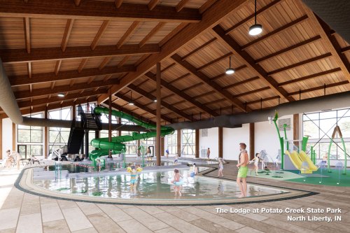 Indoor water park featuring a large slide, play area, and families enjoying the pool at The Lodge in Potato Creek State Park.