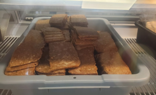A container filled with stacked, rectangular baked goods, possibly granola bars or similar snacks.