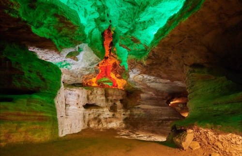 A colorful cave interior with green and orange lighting illuminating the rock formations.