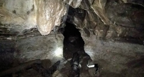 A dark cave entrance with rocky walls and faint light illuminating the ground.