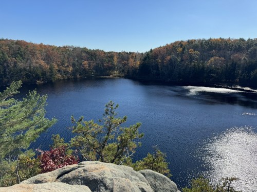A serene lake surrounded by autumn foliage and rocky outcrops under a clear blue sky.