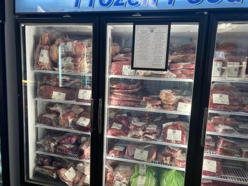 A freezer display filled with various packaged meats, including steaks and roasts, labeled and organized on shelves.