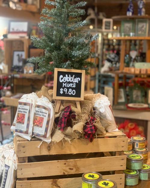 A display of cobbler mixes in a rustic setting, featuring a small tree and a price sign for $9.80.