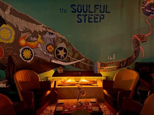 Cozy seating area with a colorful mural of a whale and warm lighting at "The Soulful Steep" café.