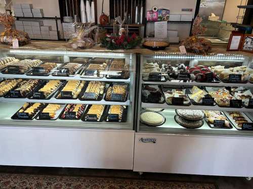 A display case filled with various baked goods, including cookies, cakes, and pastries, in a bakery setting.