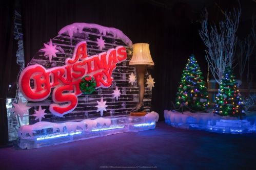 A festive display featuring "A Christmas Story" sign, a leg lamp, and decorated Christmas trees with lights.