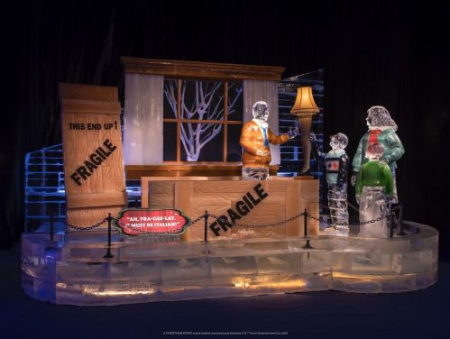 Ice sculpture display featuring a living room scene with figures, a lamp, and signs reading "FRAGILE" and "THIS END UP."