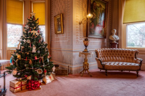 A beautifully decorated Christmas tree stands in a cozy room with a vintage sofa and elegant decor.