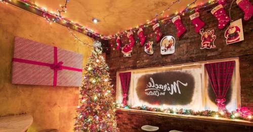 Cozy holiday-themed room with a decorated Christmas tree, stockings, and colorful lights.