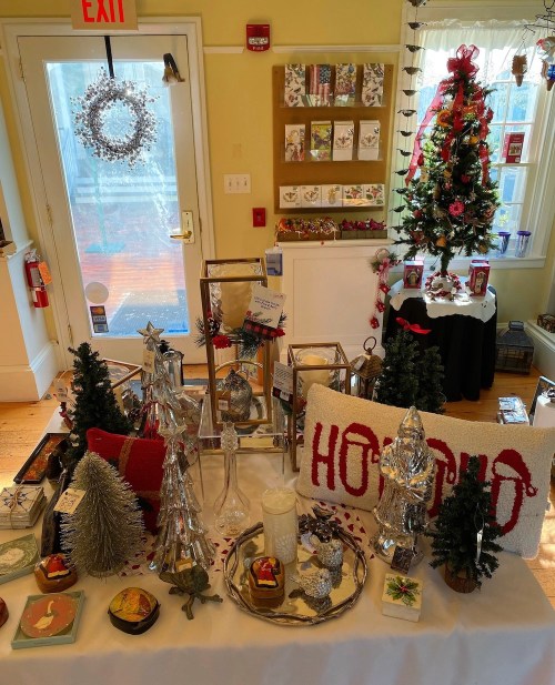 A festive display of holiday decorations, including trees, candles, and ornaments, in a cozy shop setting.
