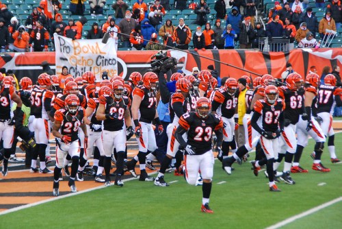 A group of Cincinnati Bengals players in black and orange uniforms running onto the field during a game.