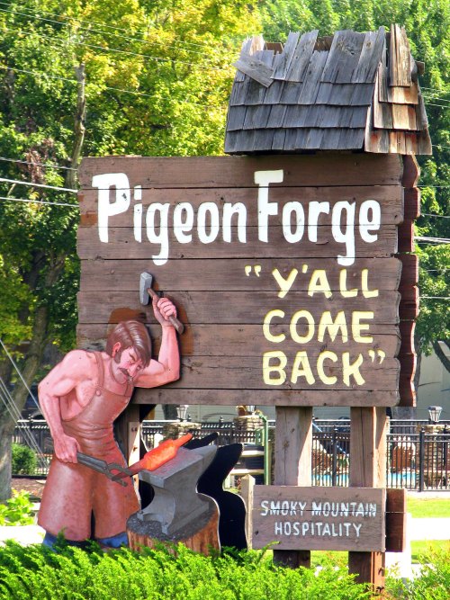 Sign for Pigeon Forge featuring a blacksmith and the phrase "Y'all Come Back" with a rustic design.