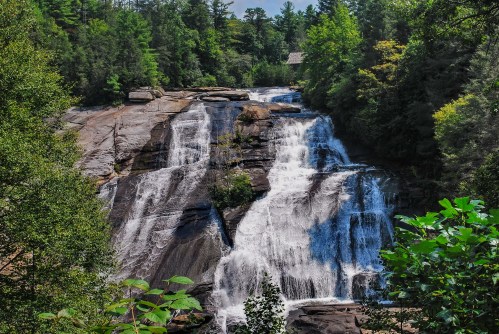 A scenic waterfall cascading over rocky cliffs, surrounded by lush green trees and foliage.