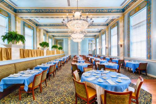 Elegant restaurant interior with blue tablecloths, chandeliers, and decorative walls, featuring neatly arranged tables.