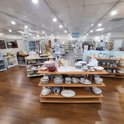 A spacious store interior showcasing various kitchenware and home decor items on wooden shelves.