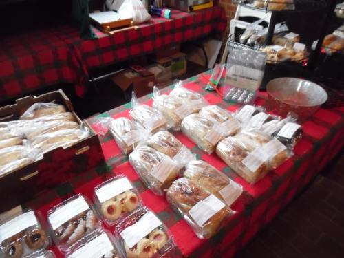 A table covered with a red and green checkered cloth, displaying various baked goods in clear packaging.