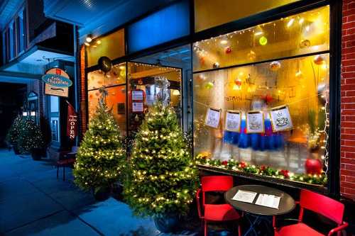 A festive café window decorated with Christmas lights and trees, showcasing holiday cheer and a cozy atmosphere.