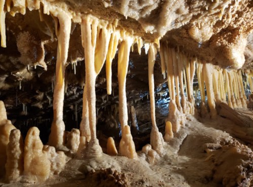 Stalactites and stalagmites in a dimly lit cave, showcasing unique mineral formations and textures.