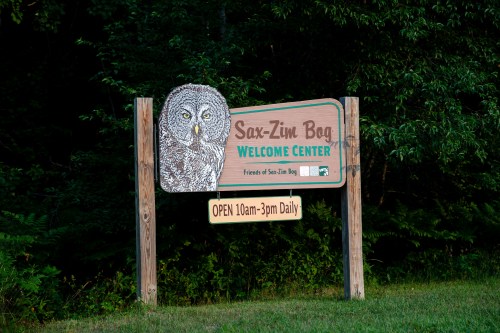 Sign for Sax-Zim Bog Welcome Center featuring an owl illustration, with hours listed as open 10am-3pm daily.