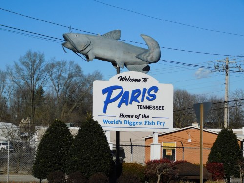 Welcome sign for Paris, Tennessee, featuring a large fish sculpture and text about the world's biggest fish fry.