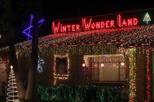A house decorated with colorful holiday lights, featuring a sign that reads "Winter Wonderland" and festive decorations.