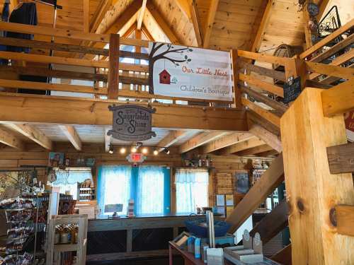 Interior of a wooden boutique with a sign reading "Our Little Nest" and a cozy, rustic atmosphere.