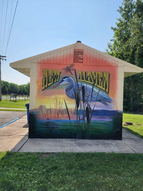 Colorful mural on a building featuring a heron, cattails, and the words "New Haven" against a sunset backdrop.