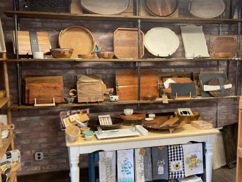 A display of wooden kitchenware and serving items on shelves, with a table showcasing various bowls and utensils.