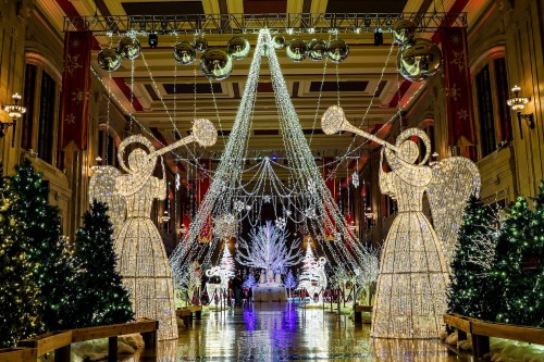A festive hall decorated with sparkling lights, two angel figures, and Christmas trees, creating a magical holiday atmosphere.