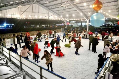 A lively ice skating rink with people of all ages skating and enjoying the festive atmosphere under string lights.