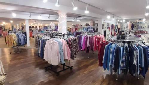 A clothing store interior with racks of colorful shirts and blouses, well-lit and spacious.