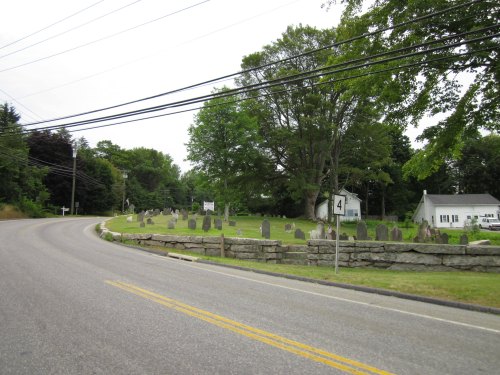 A winding road alongside a cemetery with gravestones, trees, and a house in the background. Road sign indicates Route 4.