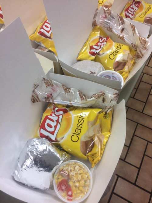Boxes containing Lay's Classic chips, a foil-wrapped item, and a cup of corn with toppings.
