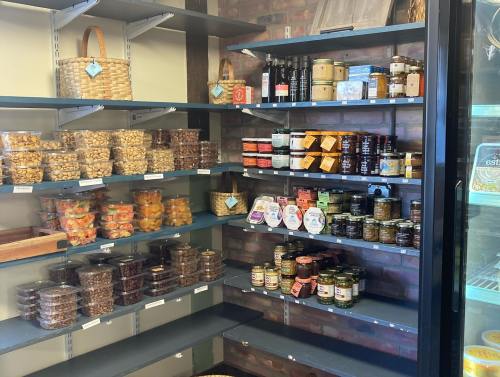 A well-stocked shelf featuring jars, snacks, and preserves in a cozy store setting.