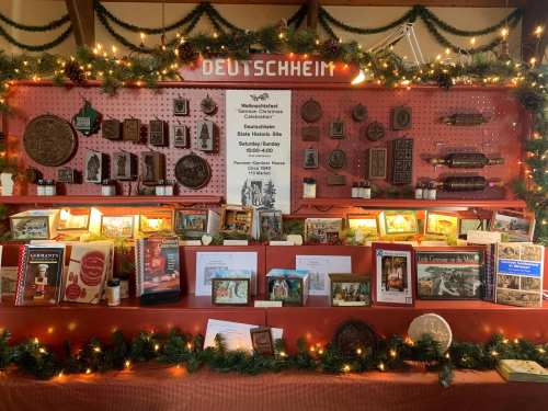 A festive display featuring various historical artifacts, books, and decorations, with "Deutschheim" prominently displayed.
