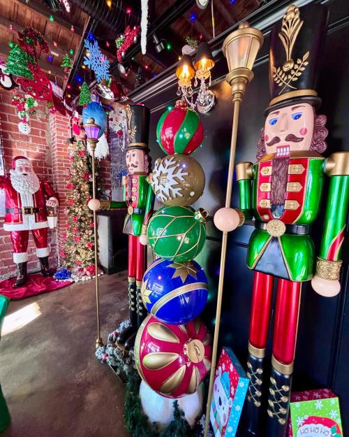 Colorful nutcracker figures stand beside festive decorations, including ornaments and a Santa figure, in a holiday-themed setting.