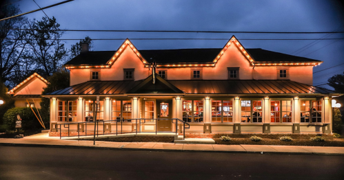 A charming restaurant illuminated at night, featuring large windows and a welcoming entrance.