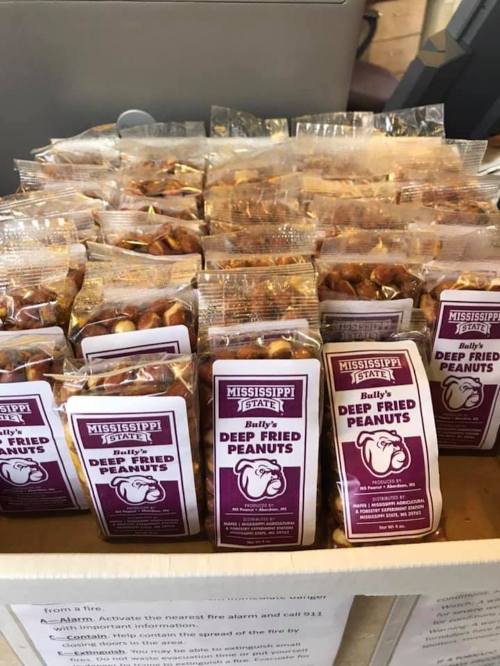 A display of packaged deep-fried peanuts in a box, labeled "Mississippi Jett's Baby's Deep Fried Peanuts."