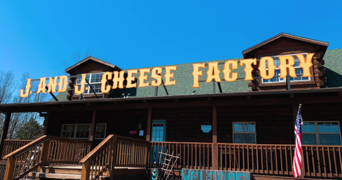 Sign for "J and J Cheese Factory" on a wooden building with a blue sky in the background.
