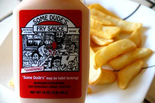 A bottle of "Some Dude's Fry Sauce" with a cartoon label, next to a plate of golden fries.