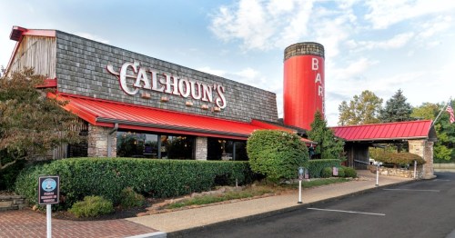 Exterior view of Calhoun's restaurant featuring a stone facade, red roof, and a large red silo marked "BAR."