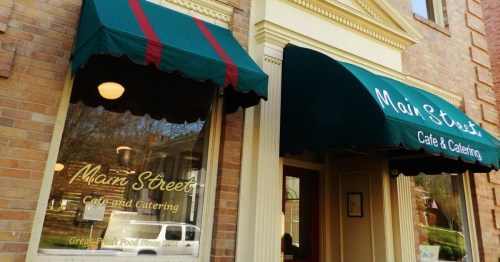 Exterior of Main Street Café and Catering, featuring green awnings and a brick facade.