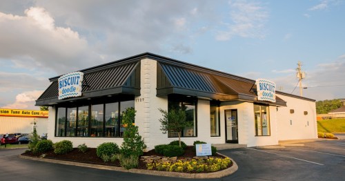 Exterior of a Biscuit Doodle restaurant with a modern design, large windows, and a landscaped parking area.