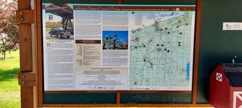 Information board featuring a historic bridge, a vintage car, and a detailed map of the surrounding area.