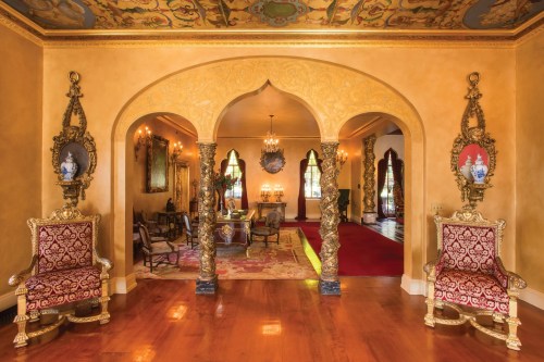 Luxurious interior with ornate arches, golden accents, and richly decorated chairs in an elegant room.