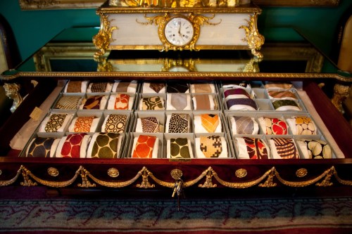 A wooden display case filled with neatly arranged fabric swatches in various colors and patterns.