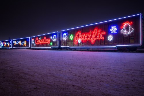 A brightly lit train car decorated with colorful holiday lights against a dark night sky.
